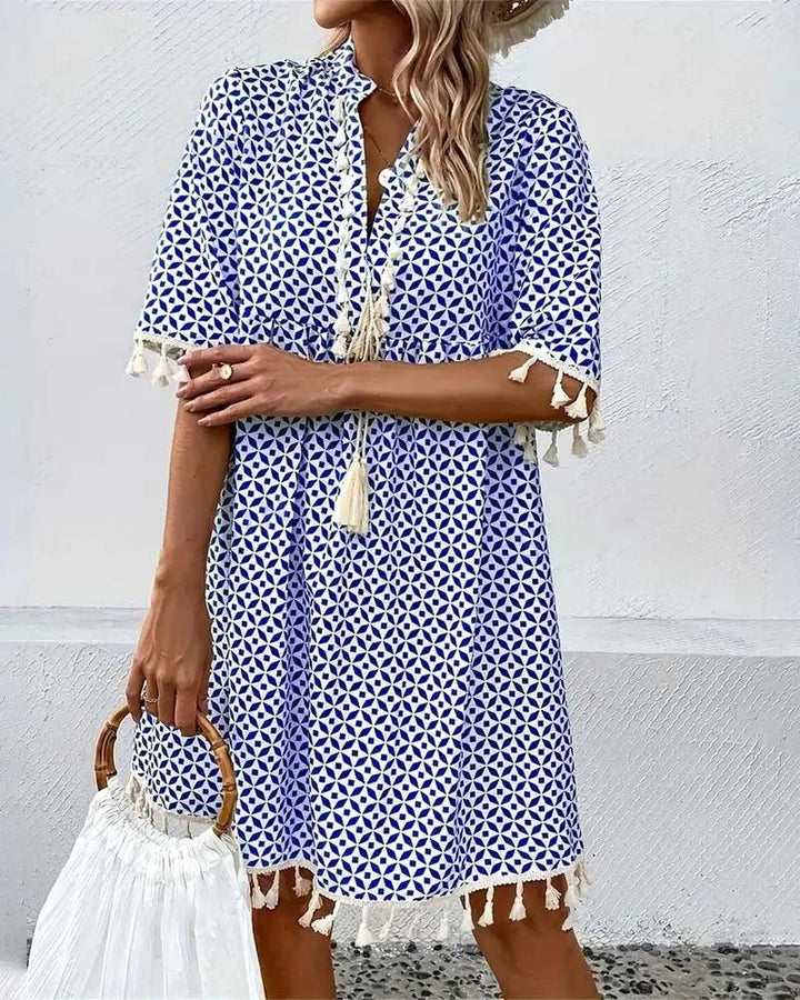 Chic women's boho mini dress with intricate geometric patterns, V-neck, and fun tassel hem for resort wear.