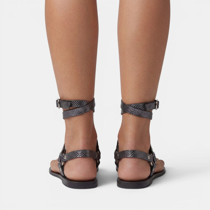 Modern women's snake print flat sandals with adjustable buckled crossover straps for a secure fit.