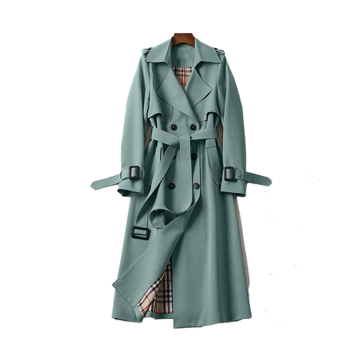 Close-up of the fabric and double-breasted detail on a women's long trench coat with a belt.