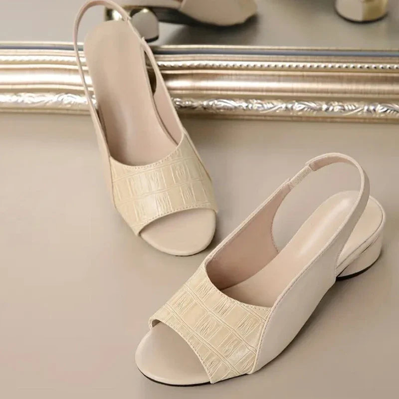 A stack of women's low block heel sandals in various colors, all with croc texture