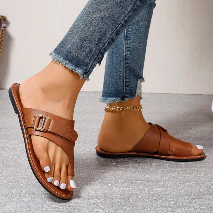 Adjustable buckle detail on women's comfortable summer sandals. Stylish open-toe flat slip-on casual footwear.