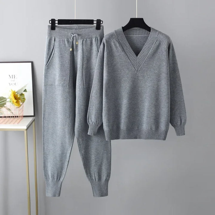 Complete women's autumn fashion outfit: cozy V-neck knit sweater and matching trousers set.