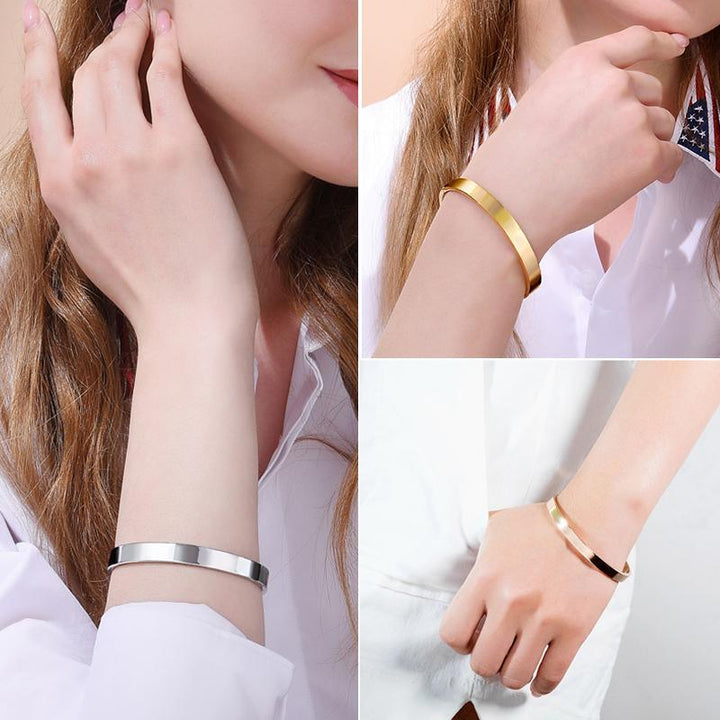 Close-up of women's stainless steel cuff bracelet with engraved crown and inspirational message