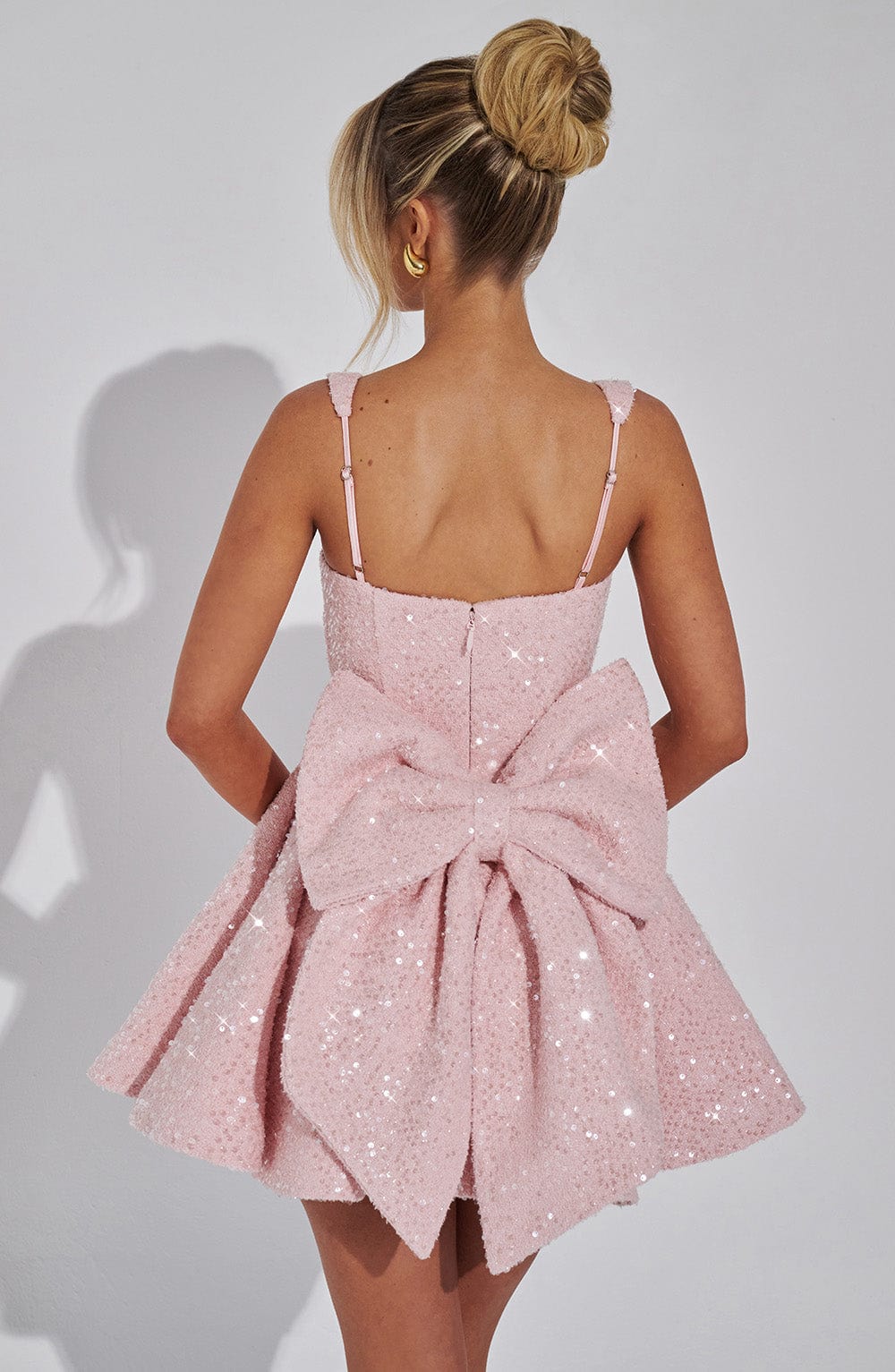 Glamorous women's sequin mini dress with backless design & large bow detail, perfect party wear.