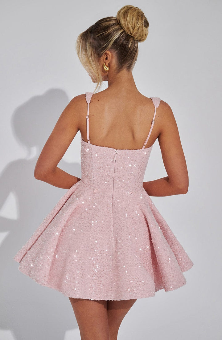 Back view of a women's backless pink sequin mini dress showcasing a large, elegant bow.