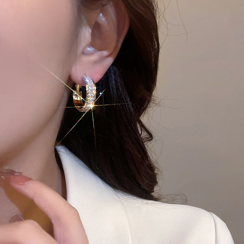 Close-up of women's small hoop earrings, silver-toned with rhinestone accents, perfect gift jewelry