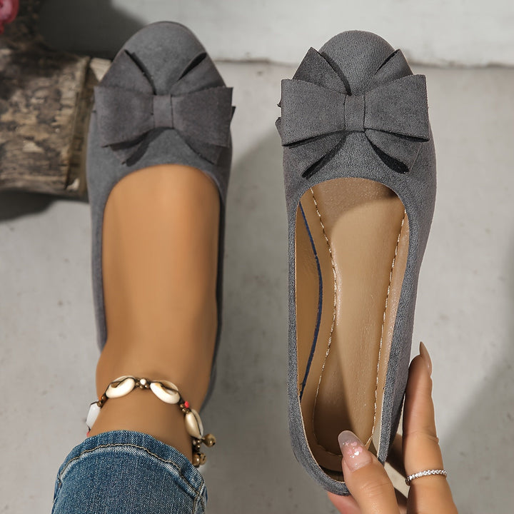 Modern ballet flat style women's slip-on wedge shoes with a decorative bow. Comfortable ladies footwear.