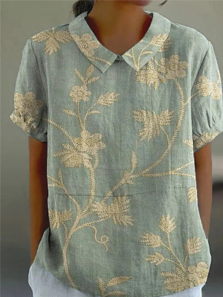 Women's embroidered floral short sleeve blouse with classic Peter Pan collar, ideal for spring fashion.