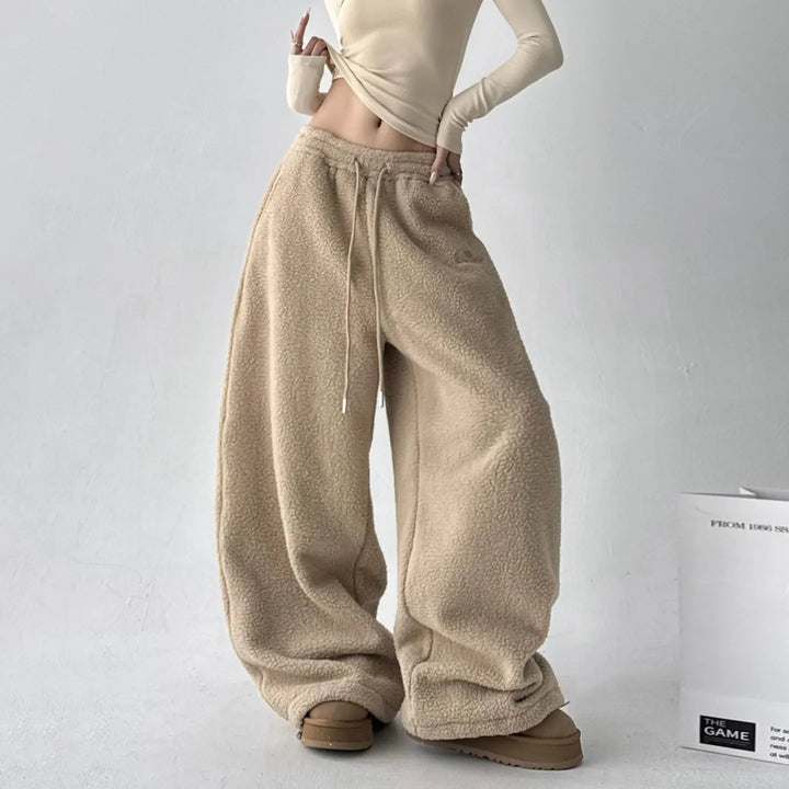 Model wearing black women's wide-leg fleece lounge pants, styled for relaxed everyday comfort