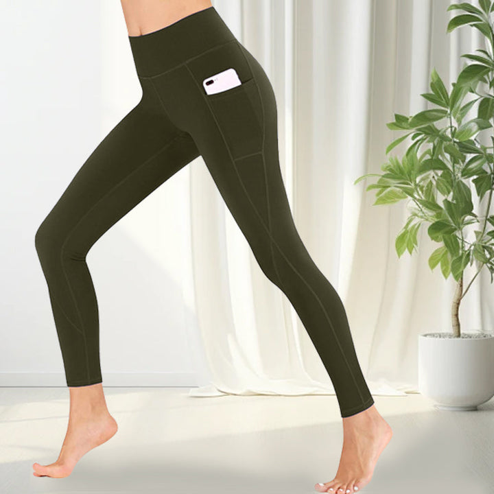 Woman stretching in high-waisted yoga leggings with functional deep side pockets.