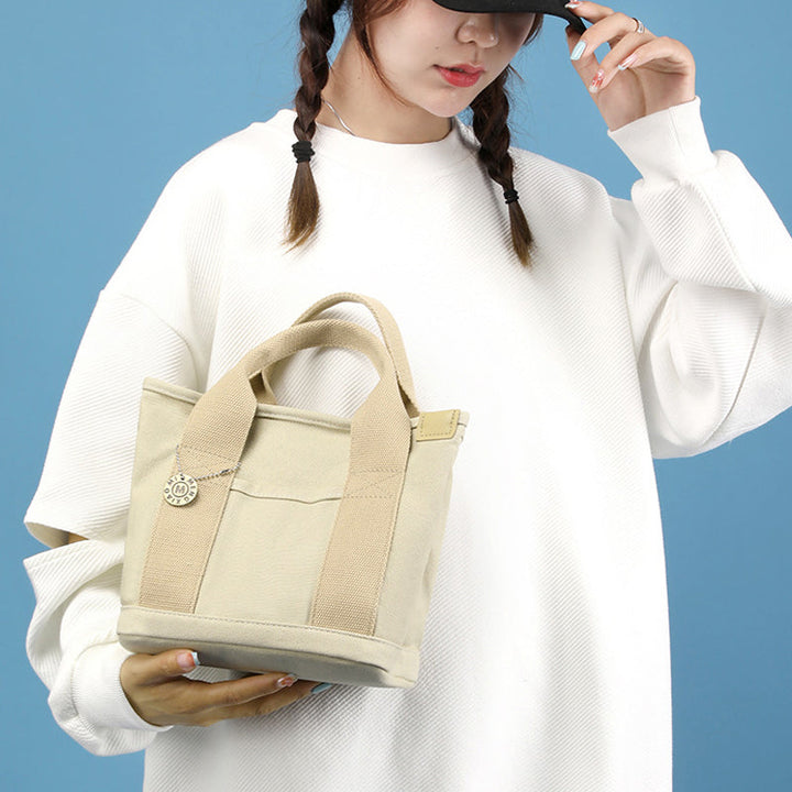 Fashionable women's canvas shoulder bag in a neutral color, showcasing its multi-pocket design