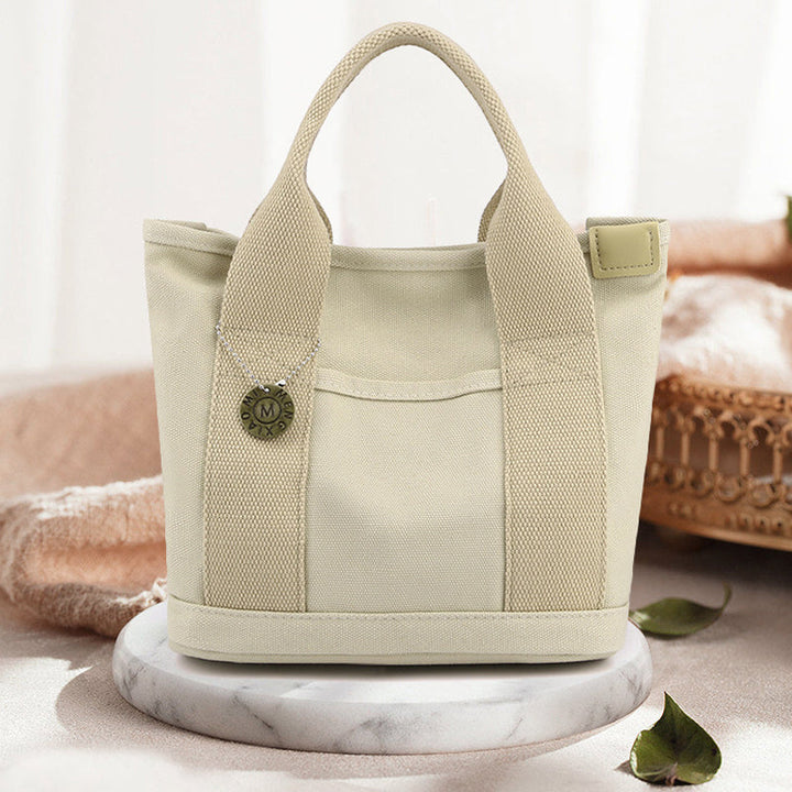 Front view of a spacious women's multi-pocket canvas handbag, great for essentials
