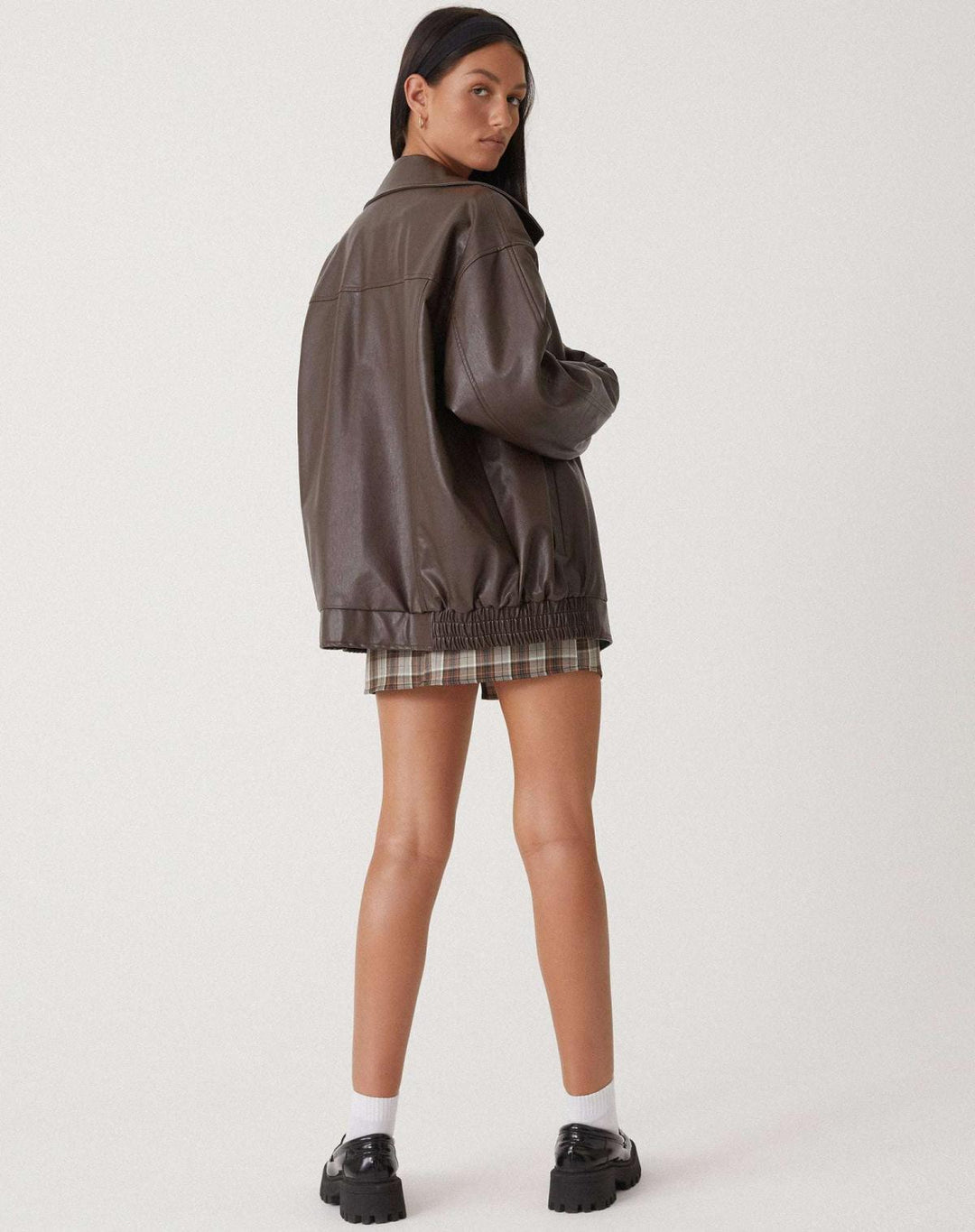Rear view of a women's oversized faux leather bomber jacket, showcasing its relaxed fall fit.