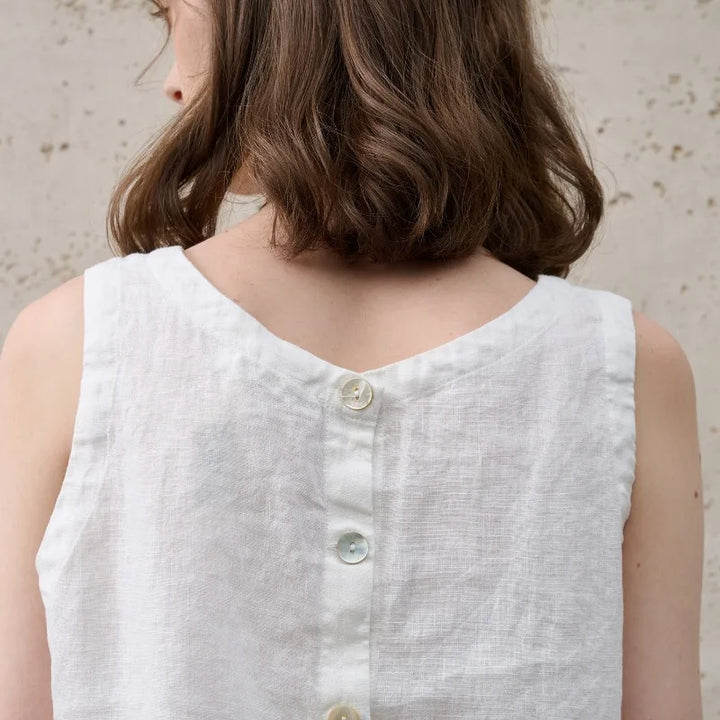 Modern minimalist pink sleeveless crop top for women, featuring an asymmetric hem and crew neck.
