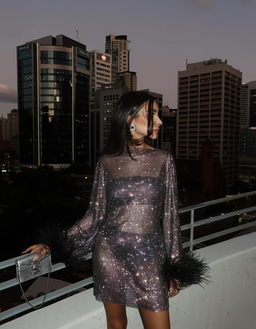 Women's sequin sheer sleeve mini cocktail dress with feather trim. Glamorous party evening wear.