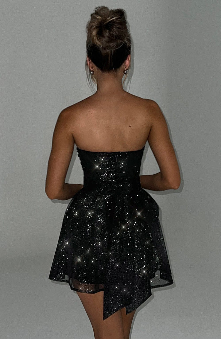 Close-up of a women's black mini dress, featuring shimmering sparkle fabric and a strapless design.