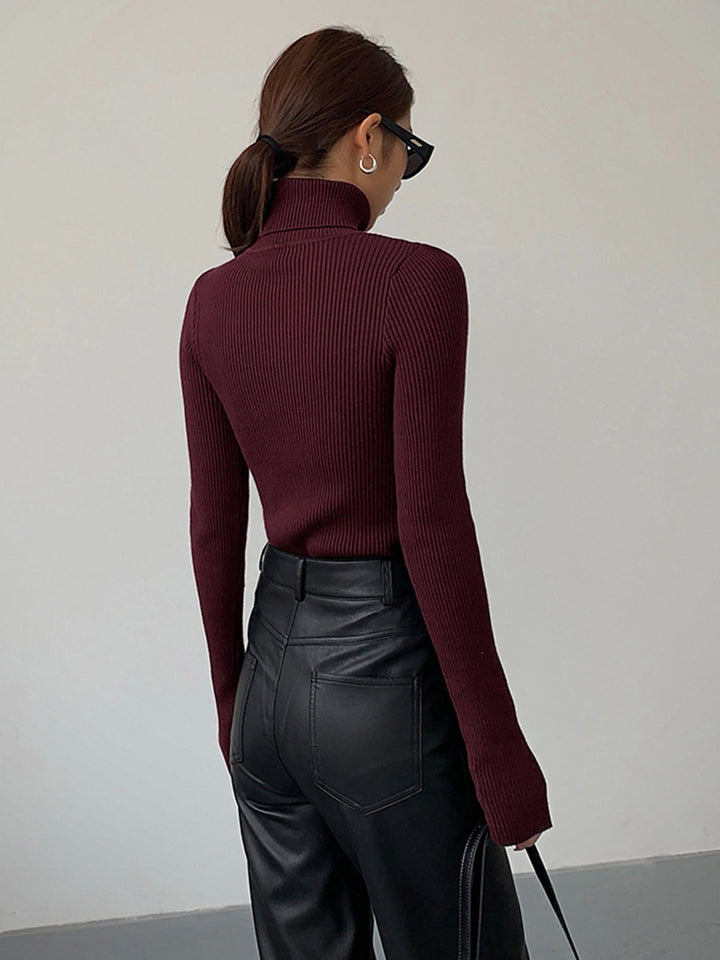 Detail shot of the ribbed texture and high neck design of a women's elegant pullover sweater.