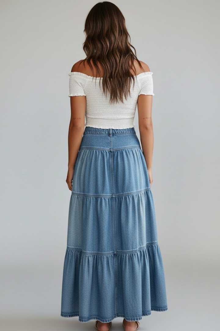 Long women's denim skirt featuring a trendy tiered design and button-front. High-waisted for a comfortable fit.