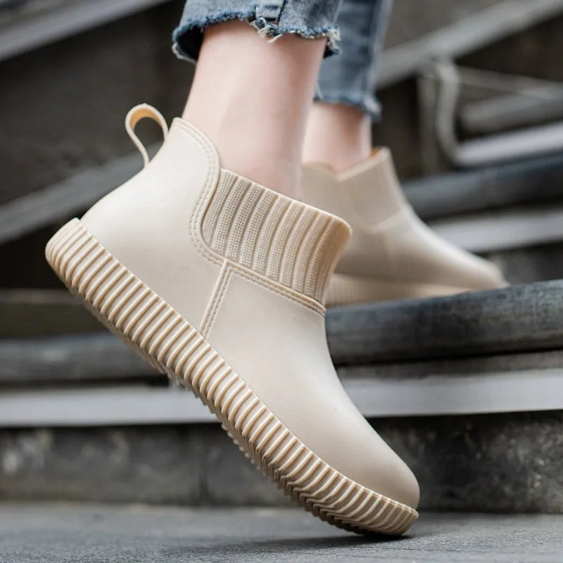 Modern women's waterproof ankle boots with a unique knitted cuff and non-slip sole for rainy weather.