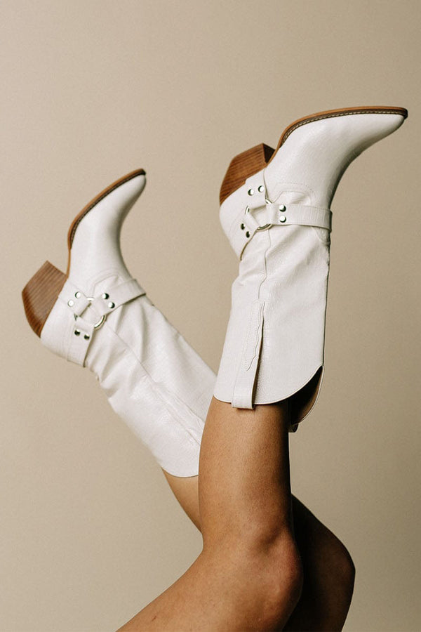 Pair of women's cow print boots with a chic belt accent, offering a modern take on classic western footwear.