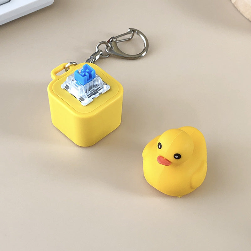 Hand holding a yellow duck sound fidget keychain, a playful stress relief gadget.